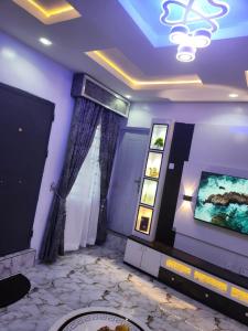 a living room with a tv and a painting on the wall at Yinmic Homes in Ikorodu