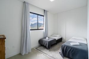 a bedroom with two beds and a window at Desfrute do melhor de Perequê a 150m do mar! CLE in Perequê