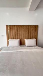 a large white bed with two pillows on it at Smartlinks apartments in Ikota +3 photos