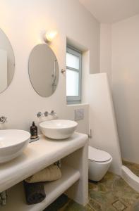 a white bathroom with two sinks and a toilet at Amorgos Elegant Houses, Villa 3 in Aegiali