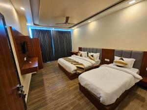 a hotel room with two beds and a tv at hotel pushkar mountain valley in Pushkar