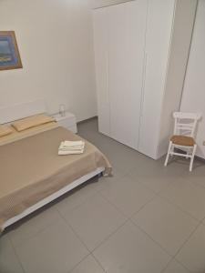 a white bedroom with a bed and a chair at Nina's house, nonno pepè in Isca Marina