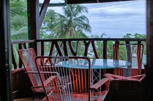 uma mesa e cadeiras numa varanda com vista para o oceano em Hotel La Isla Inn em Puerto Viejo