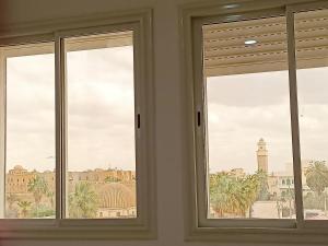 two windows in a room with a view of a city at immeuble brini in Kairouan
