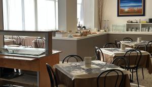 a restaurant with tables and chairs and a kitchen at Hotel Mirage in Lido di Jesolo