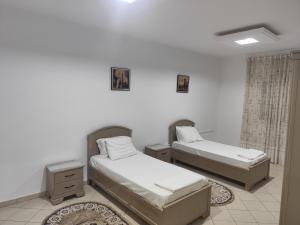 two beds in a room with white walls at immeuble brini in Kairouan