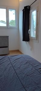 Un dormitorio con una cama azul y dos ventanas. en Charmante maisonnette 1 chambre proche de Nîmes, en Caveirac