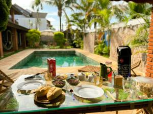ein Tisch mit Tellern voller Essen neben einem Swimmingpool in der Unterkunft Casarão 121 - Guest House in Peruíbe + 38 Fotos