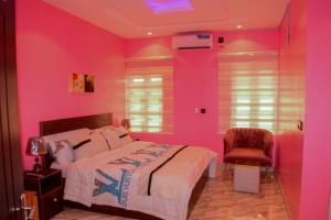 ein rosafarbenes Schlafzimmer mit einem Bett und einem Stuhl in der Unterkunft Gods Heritage Apartments and properties nig ltd 