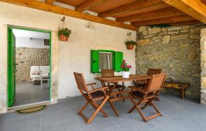 a table and chairs on a patio with green doors at House Casa Della Nonna in Kršan