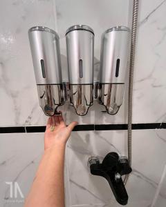 a person holding up four metal cups on a wall at Taruca Apart in Ciudad Evita