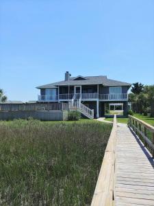 a house with a boardwalk leading to a house at Escape in Edisto Island