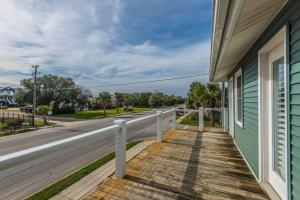 a porch of a house with a white rail and a street at Sutton House in Edisto Island