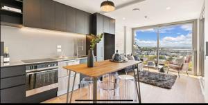 Una cocina con una mesa con sillas y una gran ventana. en CBD luxury Apartments Union green with sea view, en Auckland