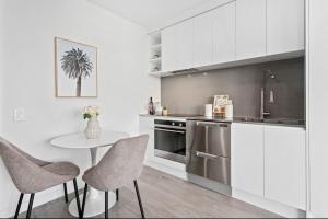 Una cocina con gabinetes blancos y una mesa y sillas. en CBD luxury Apartments Union green with sea view, en Auckland