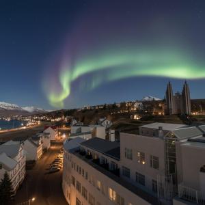 an aurora in the sky over a city with buildings at Hotel Kea by Keahotels in Akureyri
