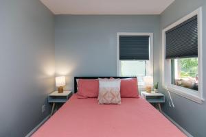 a bedroom with a pink bed with two windows at Edisto Echo in Edisto Beach