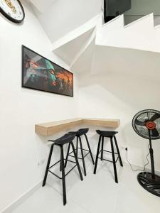 a room with two bar stools and a tv on the wall at UV Residence in Ikota