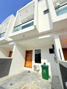 a large white house with a green trash can at UV Residence in Ikota