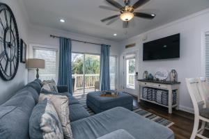 Una sala de estar con un sofá azul y un televisor. en Retreat 7B - Jubilee, en Edisto