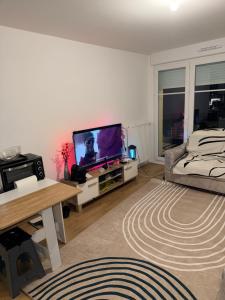 sala de estar con TV de pantalla plana y cama en Chambre d'hôte, dans 4 pièces , avec terasse, jardin, en Saint-Witz