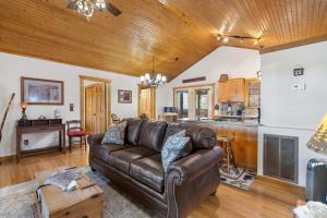 a living room with a leather couch and a kitchen at Grey Moose Lodge with Amenities Access in Branson West