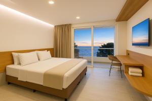 a bedroom with a bed and a desk and a large window at Stanza Del Mar in Coveñas