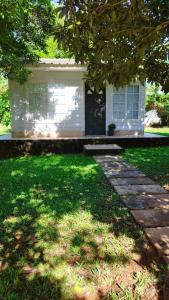 ein weißes Haus mit Veranda und Rasenhof in der Unterkunft La Comarca Tinyhouse Monoambiente in Puerto Iguazú