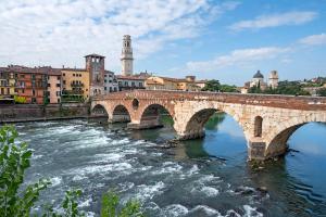 un pont en pierre sur une rivière dans une ville dans l'établissement Verona Relax & Stay APARTMENTS, à Vérone