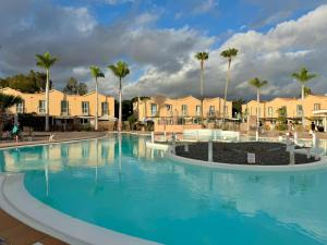 a large swimming pool with palm trees and houses at Oasis Lemon in Maspalomas