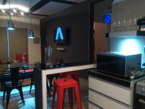 a kitchen with a bar with a microwave and a red stool at DEPARTAMENTOS BOUTIQUE DE DISEÑADOR " TERRAZA 26" - Cochera- Vista a la Montaña- CANCELACIÓN GRATUITA- PAGARÁS EN EL ALOJAMIENTO in Mendoza +43 photos