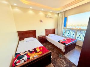 a bedroom with two beds and a large window at Al Fayrouz Palace Apartments in Luxor