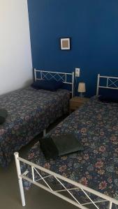 a bedroom with two beds and a blue wall at Red 4 x 4 in Camarma de Esteruelas