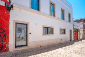 een wit gebouw met ramen aan een straat bij Primavera House in Faro