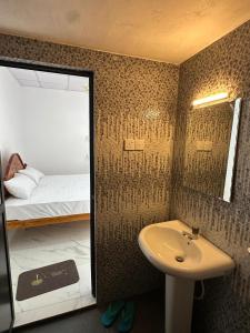 a bathroom with a sink and a bed and a mirror at Trikon Villaa in Trincomalee