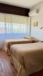 two beds in a hotel room with a window at Hotel Centenario in Atlántida