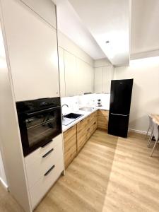 a kitchen with white cabinets and a black refrigerator at Apartament Kaszmir in Kętrzyn