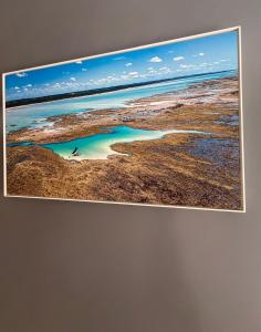 un cuadro colgado en una pared con una foto del océano en Pousada Praia Bela, en Maragogi