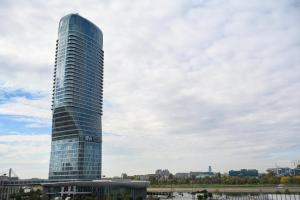 a tall glass building in front of a city at inJoy in Belgrade