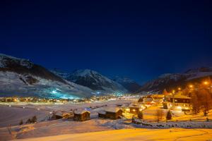 a town covered in snow at night with mountains at Arianna - Happy Rentals in Livigno