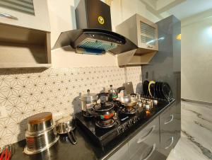 a kitchen with a stove with pots and pans at Casa de Shalom - 3 Bedroom AC Villa 65" TV in Mysore