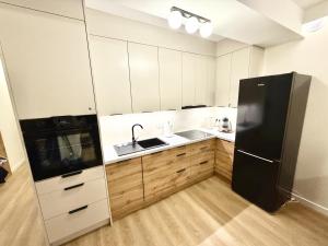 a kitchen with white cabinets and a black refrigerator at Apartament Kaszmir in Kętrzyn