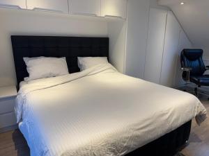 ein Schlafzimmer mit einem großen weißen Bett und einem blauen Stuhl in der Unterkunft Comfy En-suite King Size room in Hornchurch