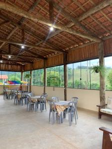 uma sala de jantar com mesas, cadeiras e janelas em Pousada Quinzitão - O seu local de descanso! em Extrema
