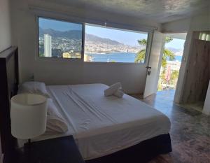 een slaapkamer met een groot bed en een groot raam bij Casa Breizh in Acapulco