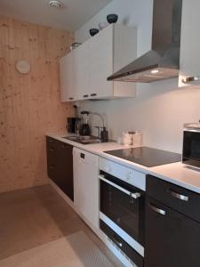 a kitchen with white and black cabinets and a sink at The other side of the CLT semi-detached house, with a separate SPA in Lahti