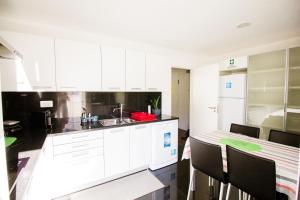 a kitchen with white cabinets and a table and chairs at Quinta da Nogueira in Funchal