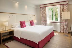 a bedroom with a large white bed and a window at Sheraton Grand Salzburg in Salzburg