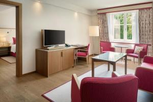 a hotel room with a television and a table and chairs at Sheraton Grand Salzburg in Salzburg