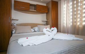 two swans are sitting on top of a bed at 3 Bedroom Nice Stacaravan In Drnis in Brištane